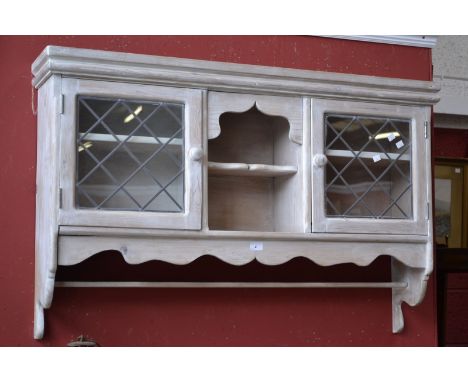 A pine wall mounted cabinet with glazed leaded light.