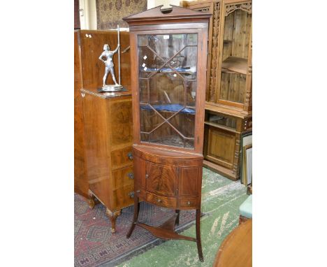 An Edwardian mahogany corner cupboard, architectural pediment, astragal glazed door to top, projecting bow front base, single