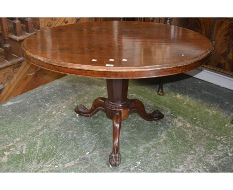 A mahogany loo table, oval top, tapering octagonal column, three cabriole legs, lion paw feet, ceramic castors