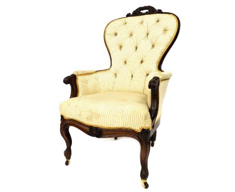 A Victorian mahogany lady's spoon back armchair, with foliate carved crest rail, overstuffed chequered cream button back fabr