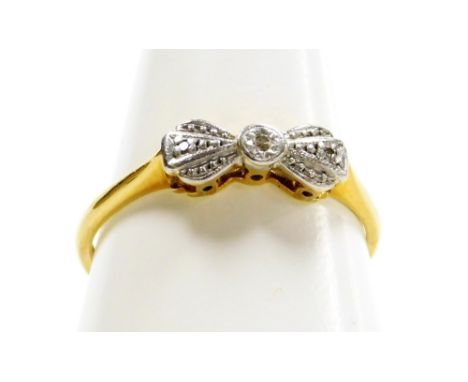 An 18ct gold bow dress ring, the bow set with tiny diamonds in platinum, on a raised shank, on yellow metal band marked 18ct,