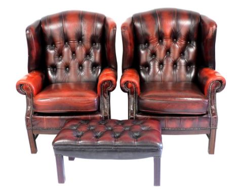 A pair of Georgian style red ox blood leather wingback armchairs, with button upholstered back and loose cushion seat, raised