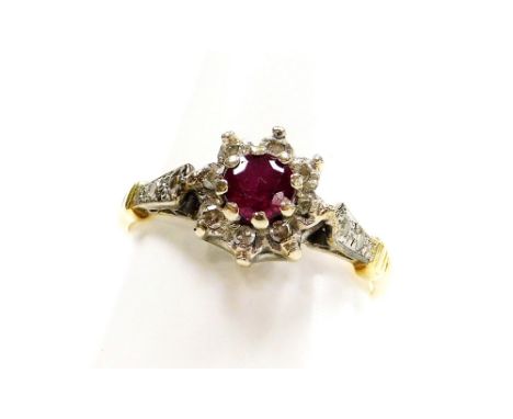 An 18ct gold ruby and diamond cluster ring, the central ruby in claw setting surrounded by tiny diamonds, with platinum and d