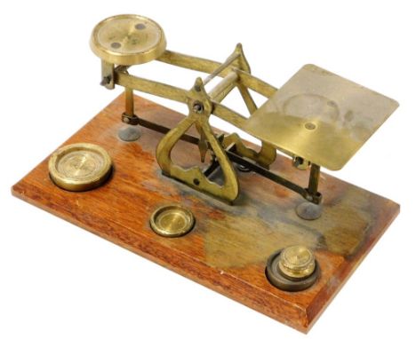 A set of vintage brass postage scales, on an oak base with various weights, the base 18cm wide. 