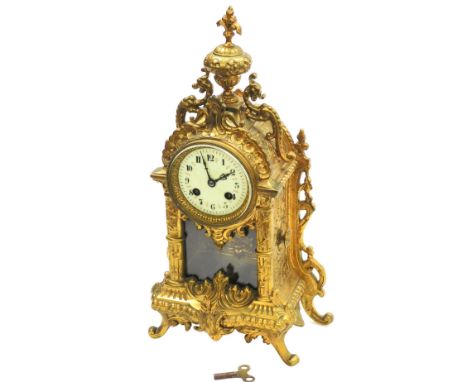 A French cast brass mantel clock, the domed top with a fleur de lis finial and applied with two dragon, with a cream enamel c