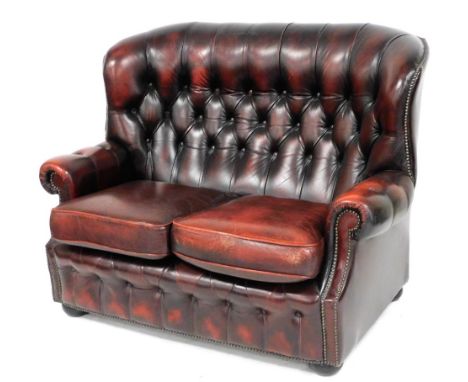 A two seater red ox blood leather sofa, with button back and front, loose cushion seats, raised on bun feet, 129cm wide.