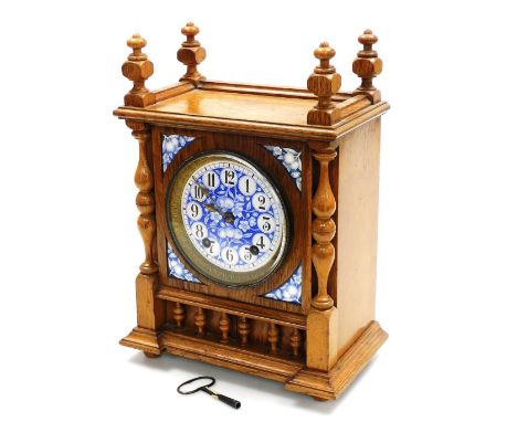 A late 19thC German oak cased mantel clock, the circular blue and white enamel dial decorated with fruit and blossom, bearing