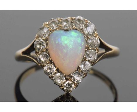 Opal and diamond ring, the heart shaped opal set within a surround of old cut diamonds and raised between pierced shoulders, 