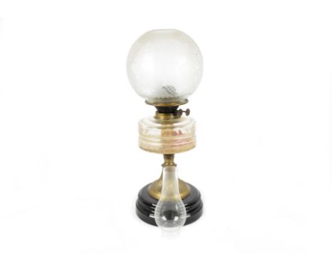 A 19th Century brass oil lamp, with a transparent glass reservoir on a metal pedestal with ceramic foot, an etched glass shad