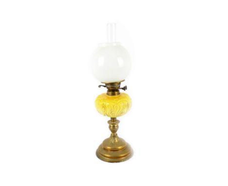 A 19th Century brass oil lamp, with a yellow ceramic reservoir on a fluted brass pedestal, a spherical opaque glass shade and
