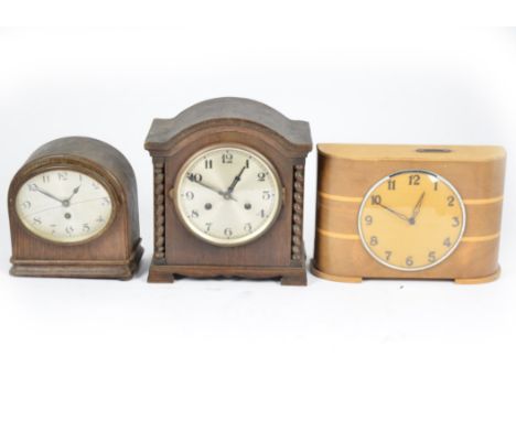 A 1950s Art Deco wooden weekly savings clock, bowed inlaid front, circular dial with Arabic numerals, top with two florins we