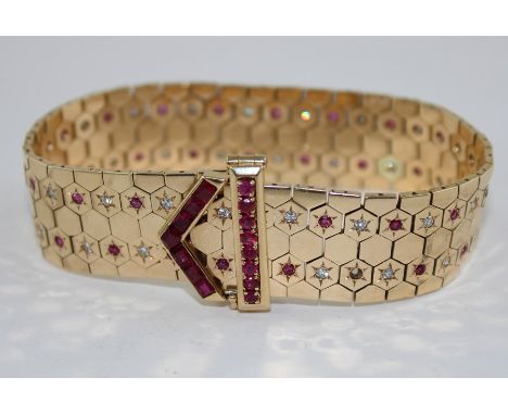 A yellow metal, diamond and ruby articulated "belt and buckle clasp" adjustable bracelet, formed from a mesh of hexagons, hav