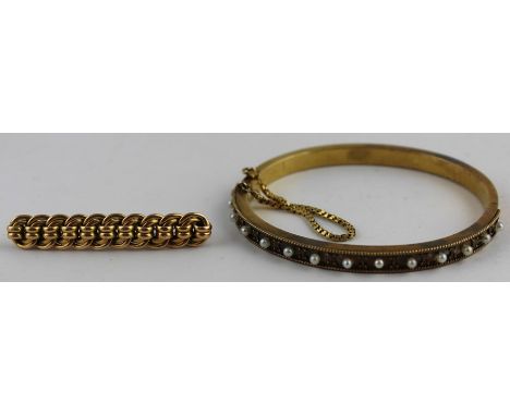 A yellow metal and seed pearl hinged bangle, of typical oval form, one half having channel decorated with filigree work borde