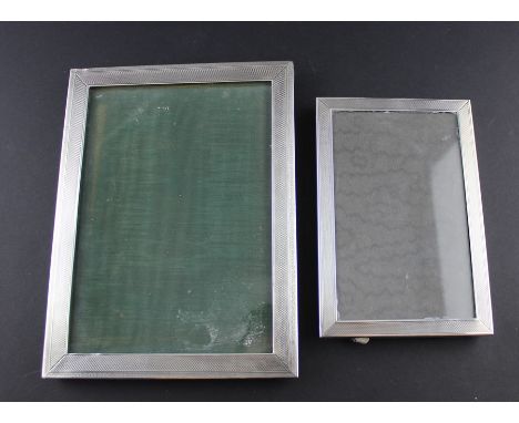 Two silver photograph frames, both of portrait rectangular form with engine turned decoration and easel backs, the larger by 
