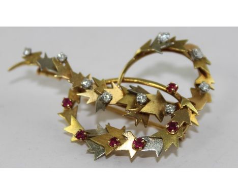 An 18ct. gold, diamond and ruby swirl brooch, the yellow gold openwork mount having two interlocking swirls with applied styl
