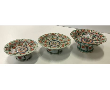 A pair of 19th Century Chinese famille rose stem cups, the bowls with plain interiors decorated with blossom in a garden sett