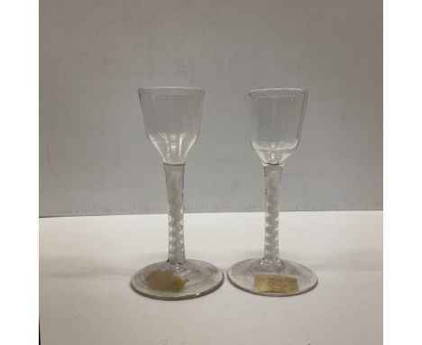 A pair of 18th Century glass wines with plain bowls on white enamel twist stems, raised on a circular foot, both bearing labe