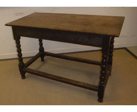 An 18th Century oak side table, the plank top above a plain frieze with moulded base, on bobbin turned supports to blocks uni