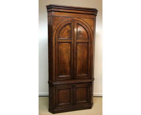 A George III mahogany freestanding corner cupboard, the moulded cornice above a satinwood strung frieze and two domed cupboar