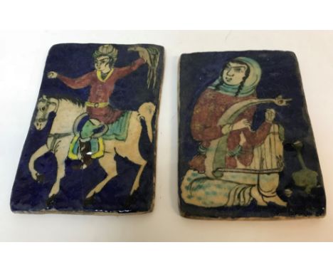 Two Quajar blue ground pottery tiles, one depicting a "Falconer on horseback", 21.7 cm x 14 cm, the other depicting "Seated l