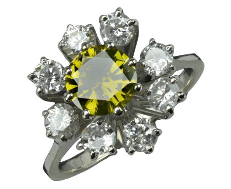 A diamond cluster ring, the central brilliant-cut diamond of yellow tint within an undulating surround of brilliant-cut diamo