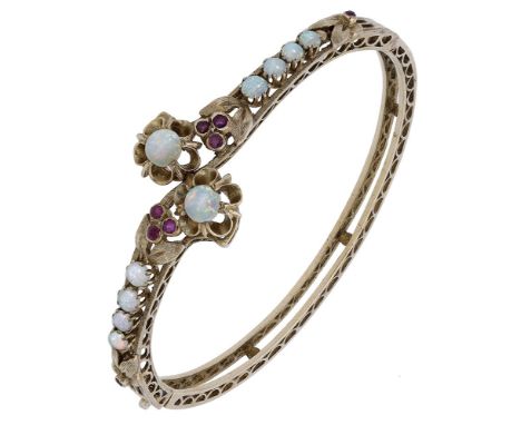 An opal and ruby crossover bangle, the hinged bangle set to the front with opal cabochons and circular-cut ruby accents, high