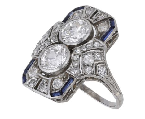 An Art Deco diamond dress ring, circa 1920, set with two old brilliant-cut diamonds in a pierced plaque surround set througho