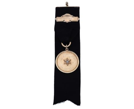 An early 20th century gold and diamond set presentation medallion on fob, the black grosgrain ribbon suspending a gold bar an