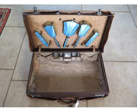 A Vintage leather ladies suitcase with a fitted interior of enamel brushes and chrome plated bottles with outer fabric wrap -