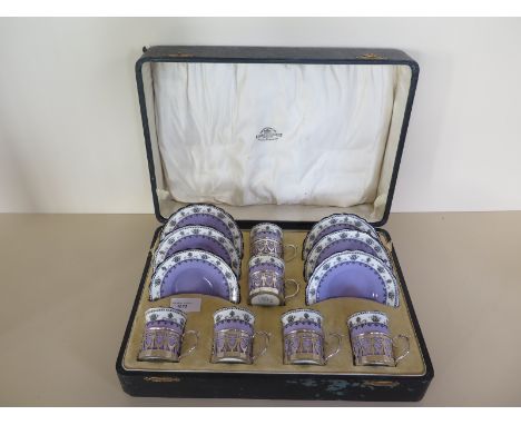 An Aynsley set of six coffee cans and saucers with silver cup holders hallmarked Birmingham 1919/20 in presentation box, one 