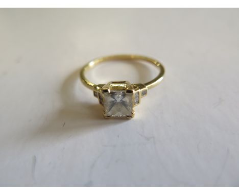 An 18ct yellow diamond ring set with a central princess cut diamond measuring approx 6mm square approx 1ct flanked either sid