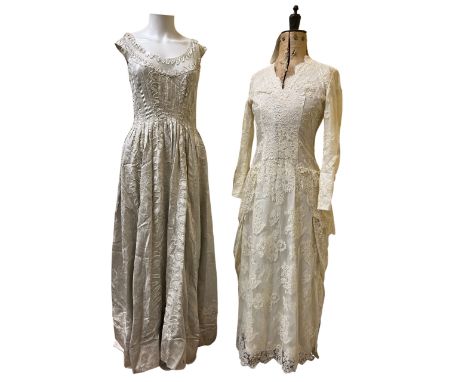 A 1950s wedding dress in a silver white satin brocade with silver threads. The bodice has vertical darts all around and the s