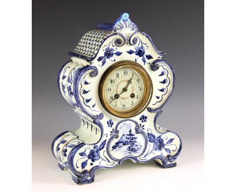 A blue and white tin glazed earthenware clock in the manner of Delft, the 'C' scroll moulded case enclosing the 10cm enamelle