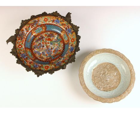 A Chinese porcelain celadon glazed and silvered bowl, the shallow bowl decorated in white relief with peonies surrounding a c