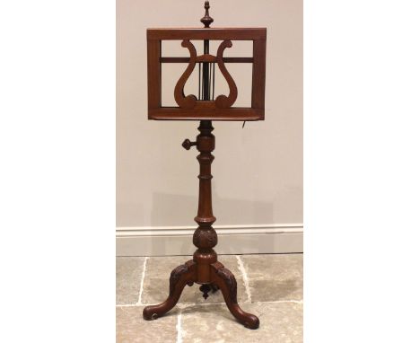 A Victorian walnut music stand, with twin lyre shaped easel rests, upon a tapering fluted column and three leaf carved cabrio