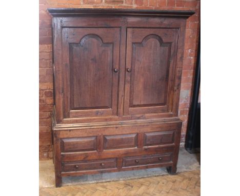 A mid 18th century oak livery cupboard, the cavetto cornice over a plain frieze centred with the initials 'W T M', a pair of 