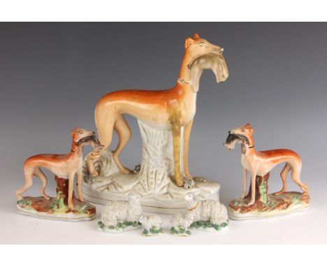 A Staffordshire greyhound of large proportions, modelled standing with a hare in its mouth, 28.5cm high; with a pair of small