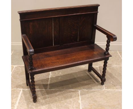 A late 19th/early 20th century oak settle, the twin panelled back rest extending to straight arms with rounded terminals, upo