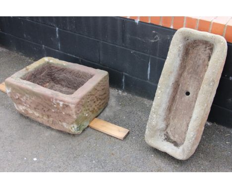 A rectangular sandstone trough, 29cm H x 59cm W x 45cm D, along with a reconstituted trough, 14cm H x 74cm W x 31cm D (2)