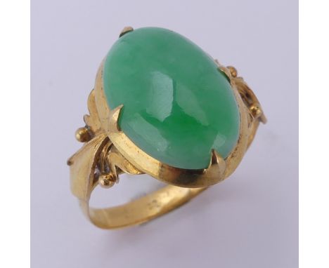 A Chinese jade Ring, the oval cabochon stone approx. 15mm long, in a four claw mount, tested as 18ct gold, Size P, 4.2g.