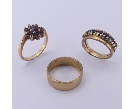 Three 9ct gold Rings; one a plain band, Size K,&nbsp; one set sapphires with split shoulders, Size J, the other a garnet clus