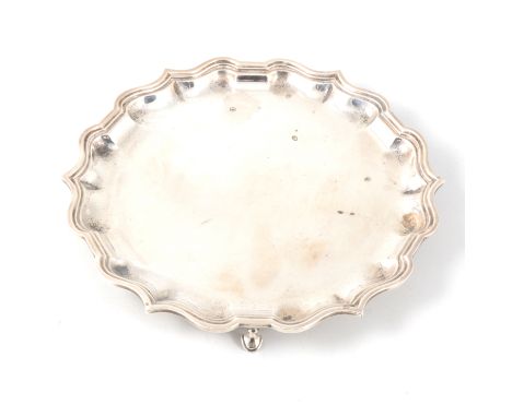 A small silver salver with chippendale style border supported on three hooved feet, 20cm diameter, hallmarked Birmingham 1924