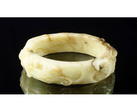 A Chinese green jade bangle, 20th century, carved with trailing chi dragons, 8.5cm diameter CONDITION REPORT: In good conditi