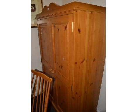 A contemporary pine two door wardrobe, cupid's bow pediment, panelled doors, button handles, plinth base. 168cm high x 100cm 