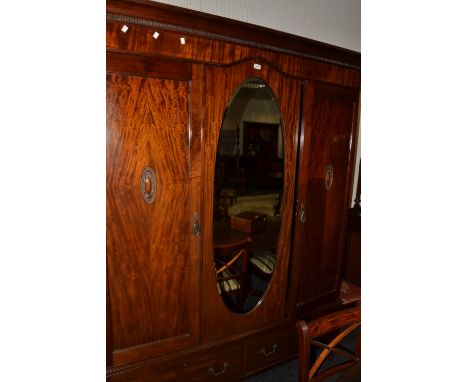 An early 20th century mahogany two piece bedroom suite, comprising double door wardrobe with central oval mirror and dressing