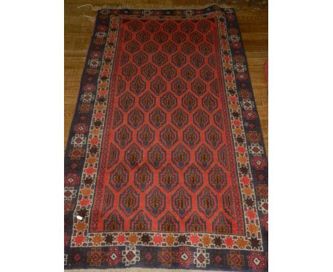 A red ground carpet, having many diamond shaped medallions to centre, within geometric borders, fringed