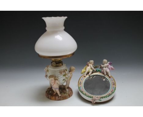 A CONTINENTAL STYLE MIRROR WITH CHERUBIC DECORATION, together with a similar oil lamp, H 35 cm (2)Condition Report:part of bo