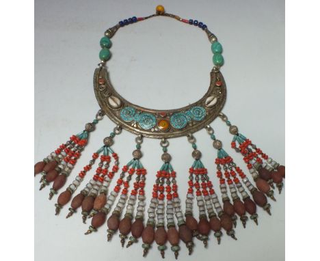 A VINTAGE EASTERN WHITE METAL TRIBAL NECKLACE, adorned with beads, unpolished agate and cowrie shells etc.