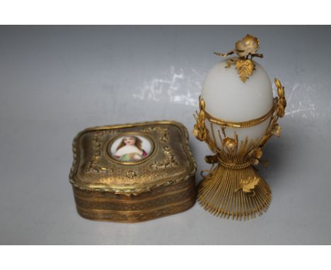 A GILT METAL OVAL JEWELLERY BOX INSET WITH A MINIATURE PORCELAIN PORTRAIT OF A LADY,  together with a gilt metal mounted egg 