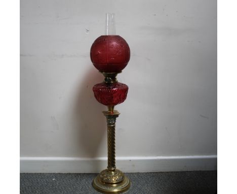 A VICTORIAN BRASS COLUMN OIL LAMP, with cranberry glass oil reservoir and cranberry shade, the burner named 'Evered & Co, Bir